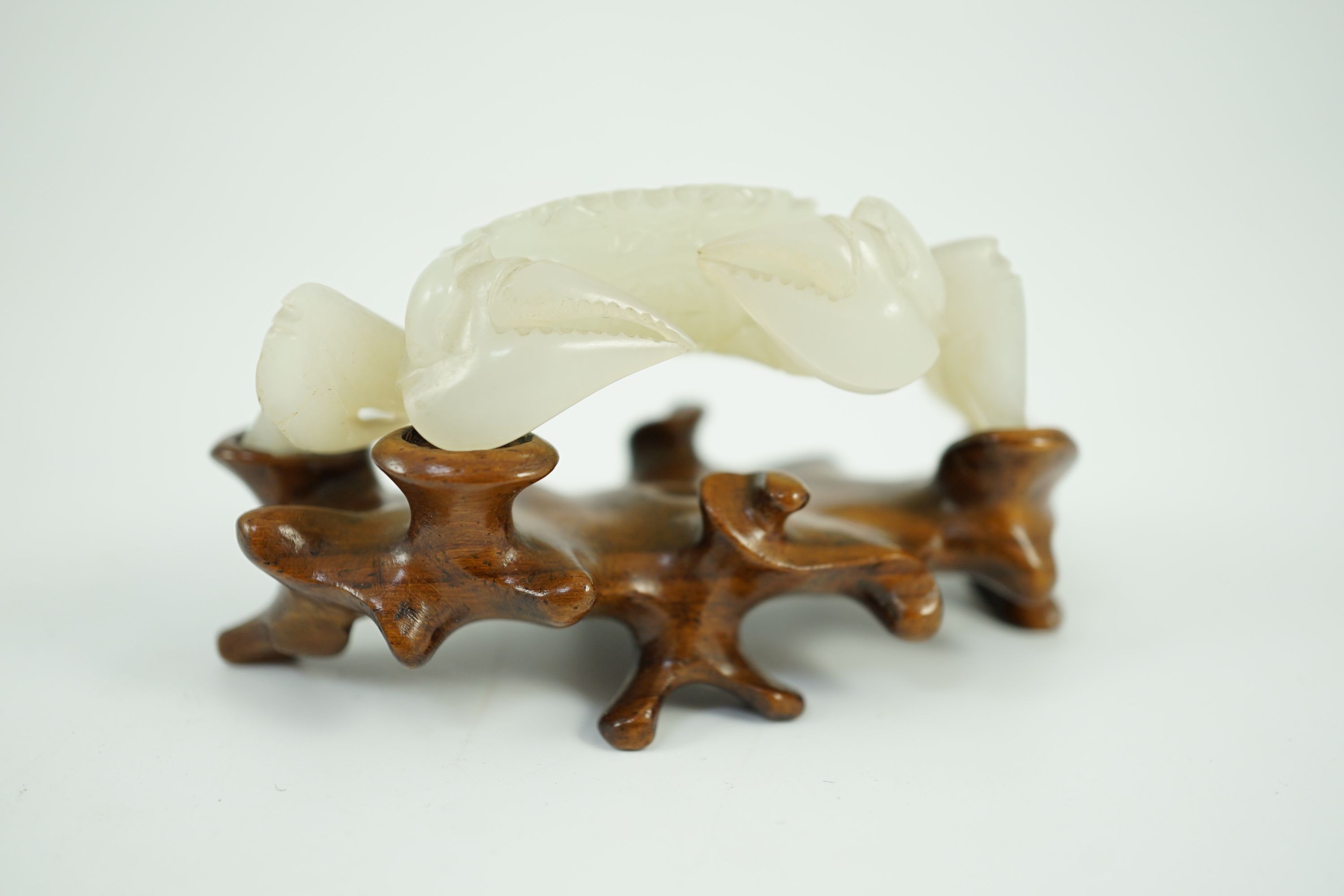 A Chinese pale celadon jade model of a crab, 20th century, 8.4 cm wide, wood stand